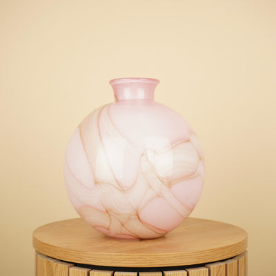 Ronde roze vaas met crème en beige marmerpatroon en korte hals op een houten tafel